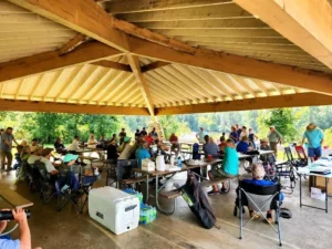 A group of people sitting at tables in the shade.