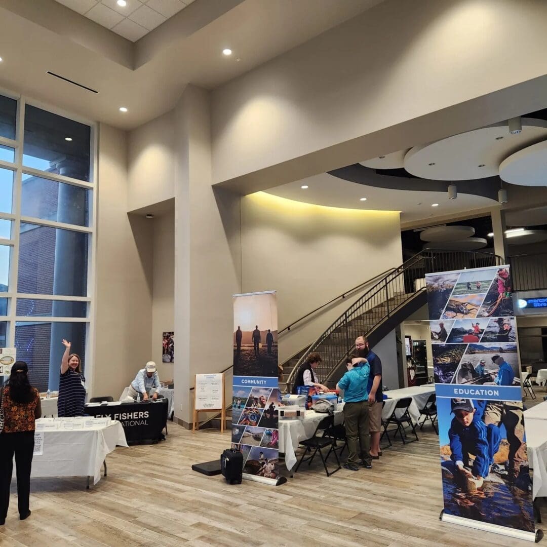 People are gathered around tables with banners labeled 