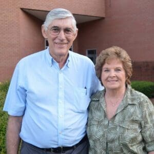 A man and woman standing in front of a brick building.